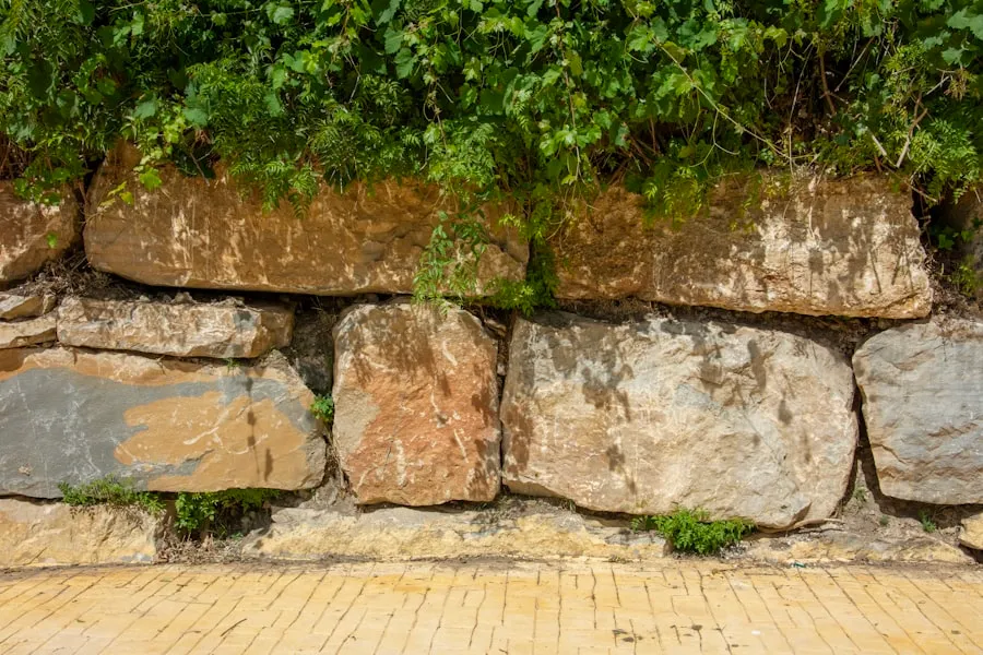 Maçon assemblant un muret en pierre sèche dans un jardin