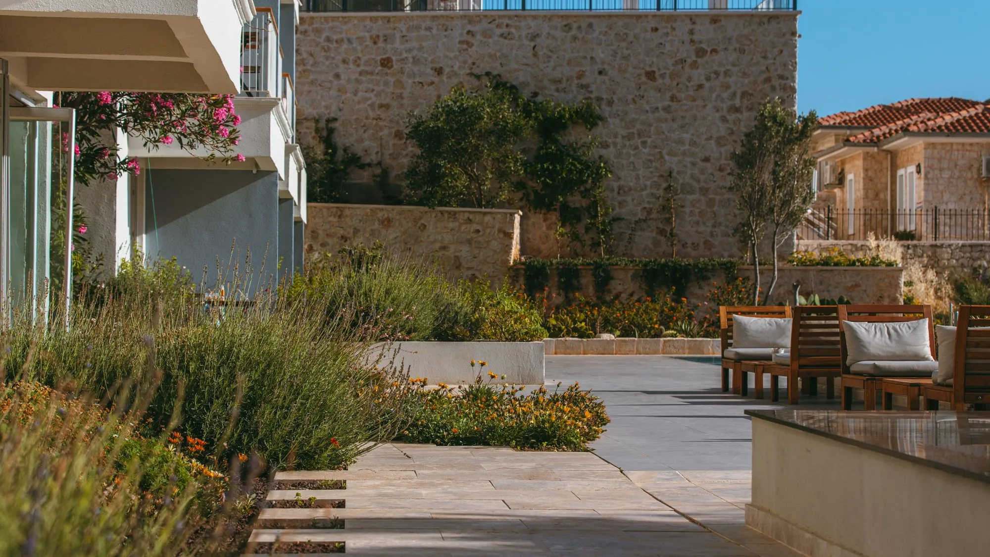 Terrasse de pierre et massifs plantés devant une maison méditerranéenne